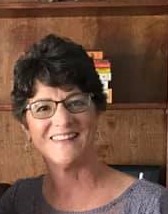 Head shot of Diane Mueller, white woman with short brown hair with glasses smiling