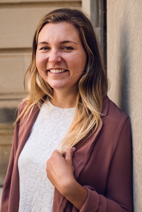 This is a photo of Kiley McLean standing next to the UW-Madison School of Social Work. 