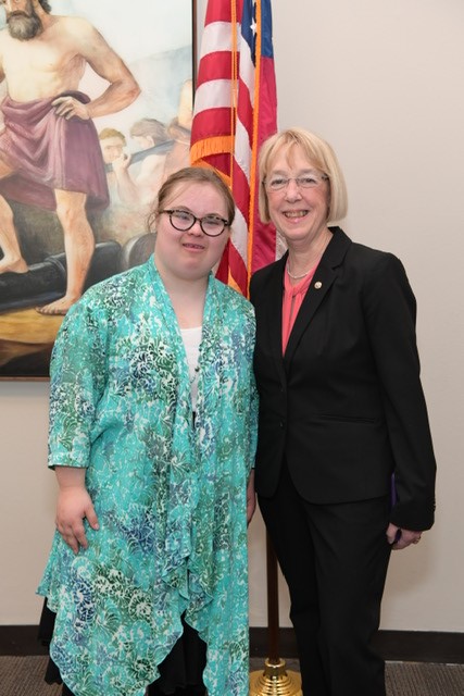Helen Nash and Senator Patty Murray standing together and smiling in front of an American flag in a hallway in a Senate office building.
